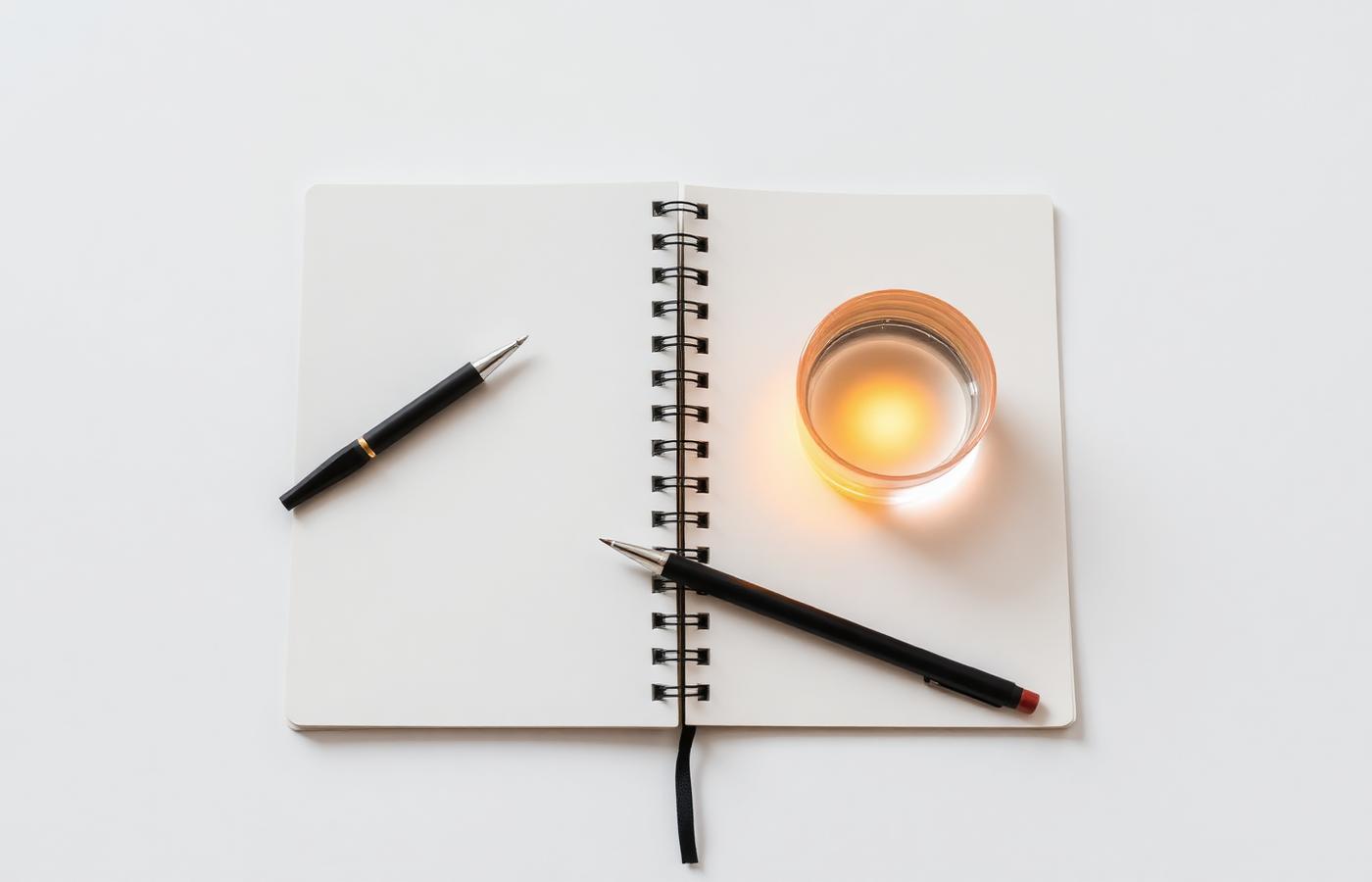 Open notebook, mechanical pen and glass of water lit by warm light